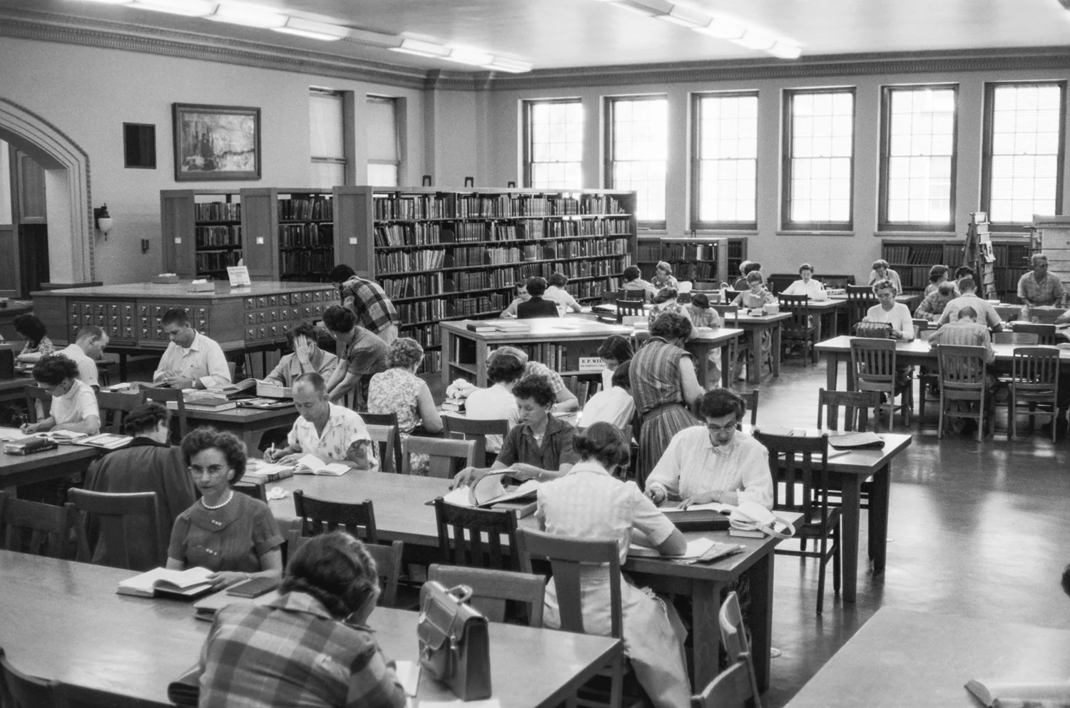 Students with books at tables in a library