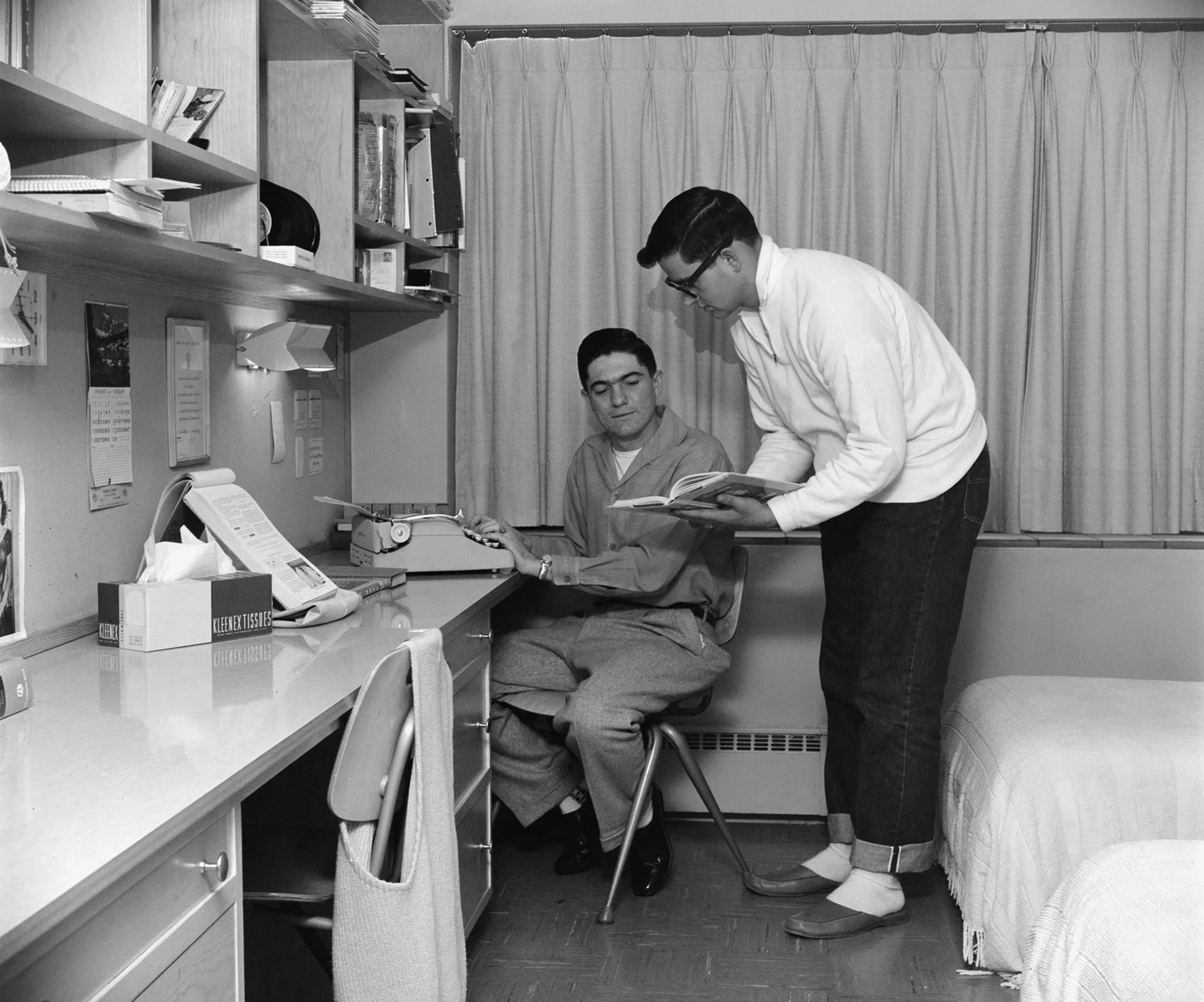 Two students working on a writing project in a dorm room