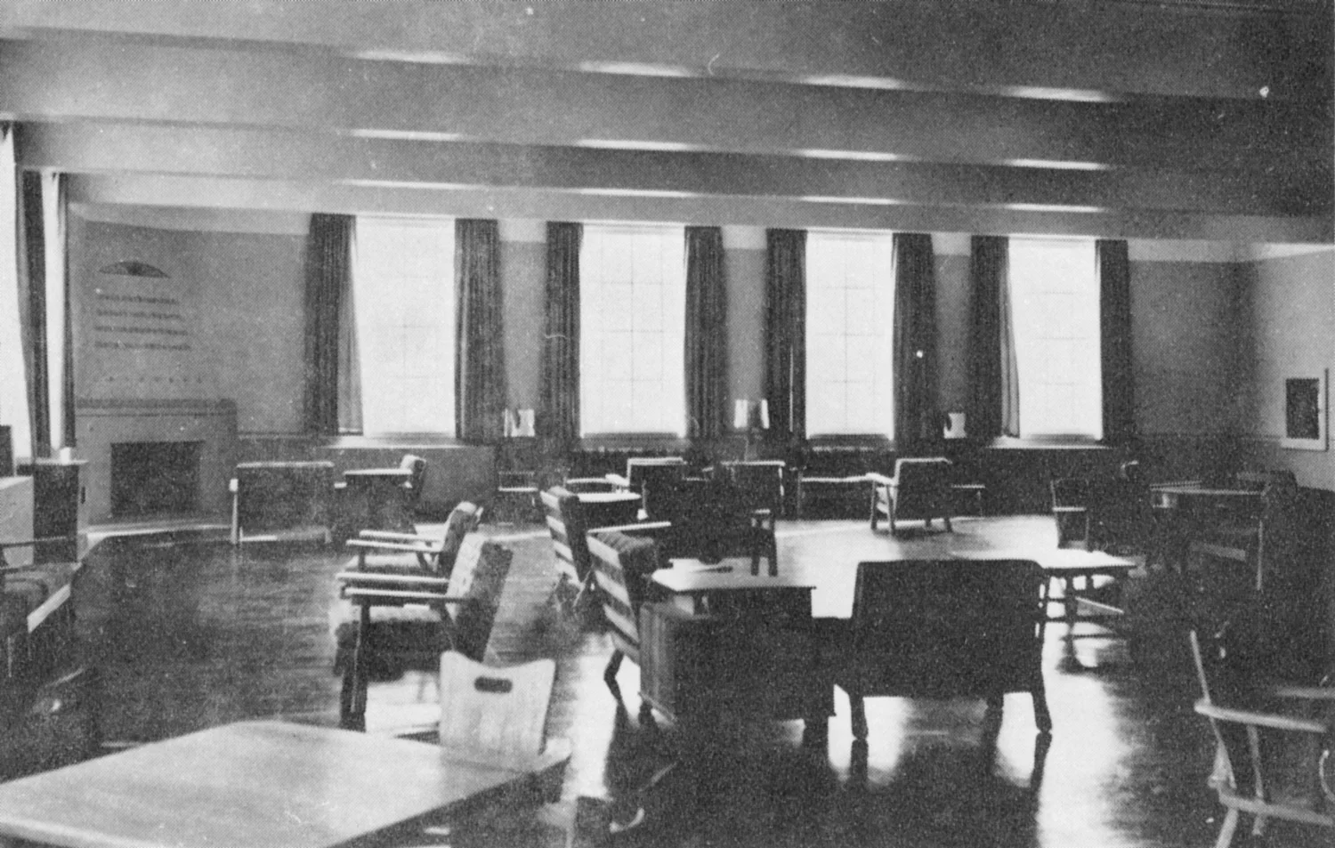 Tables and chairs in a public room with a fireplace and tall windows