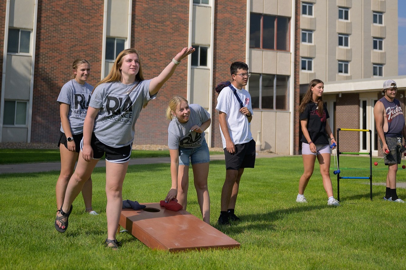 The image is of students playing cornhole.