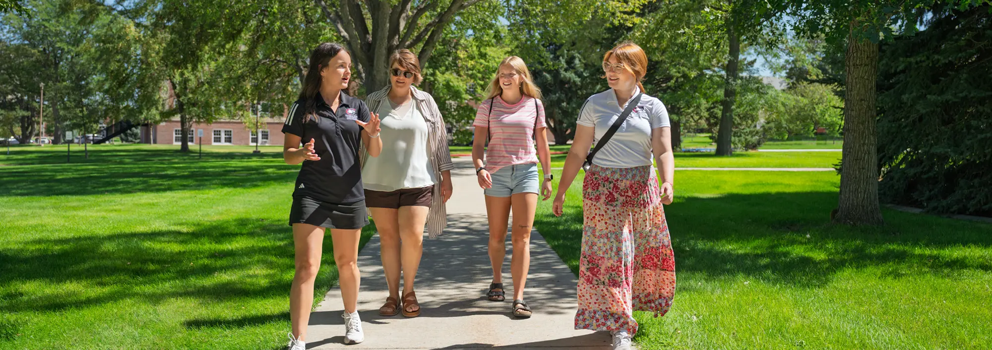Two students lead a campus visit with a parent and child