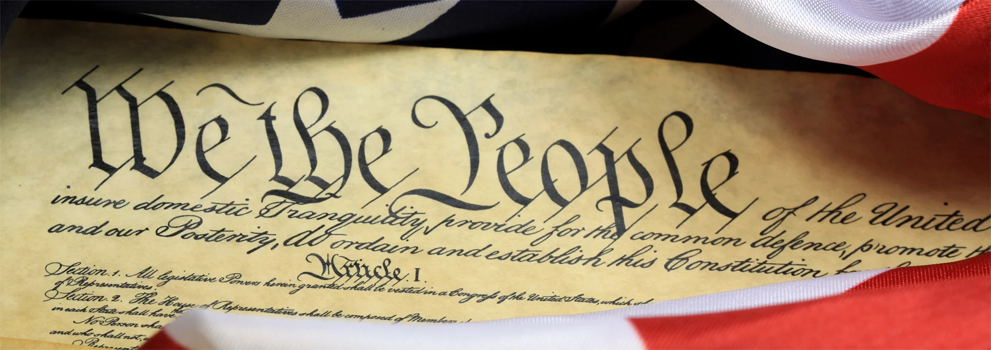 Closeup view of the opening text to the United States Constitution framed by the United States flag