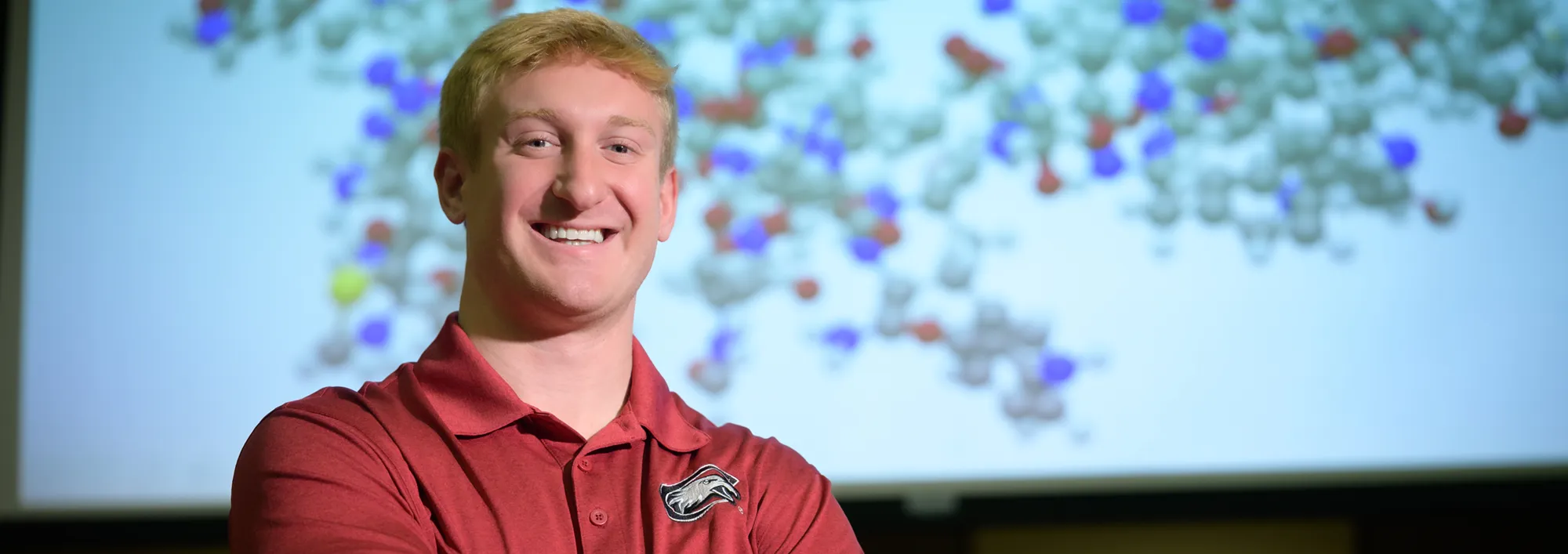 Student standing in front of a molecular diagram