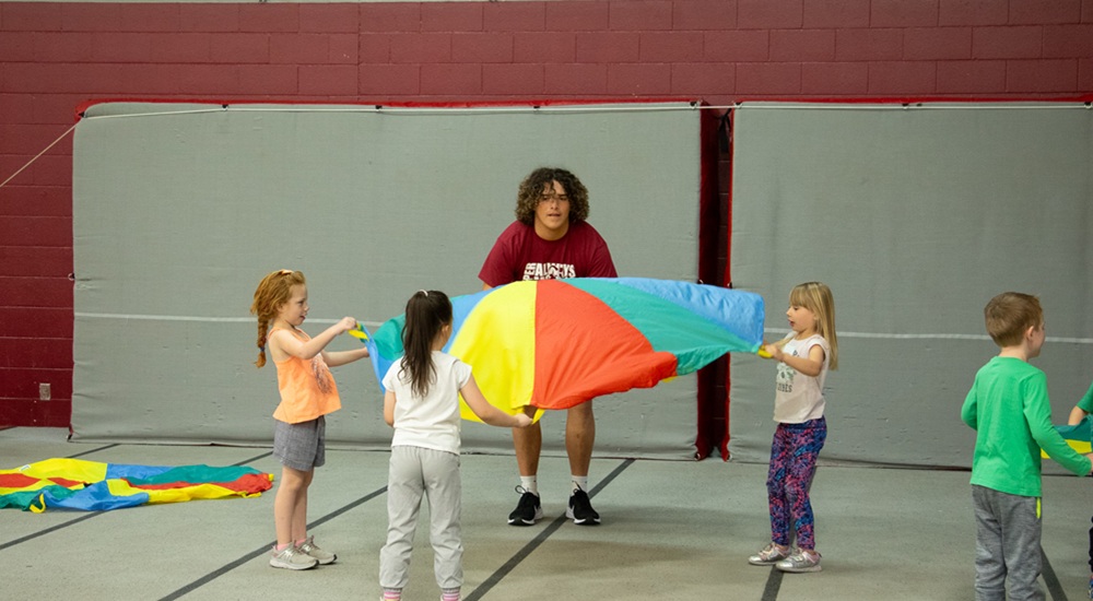 Elementary children playing with parachute in gym