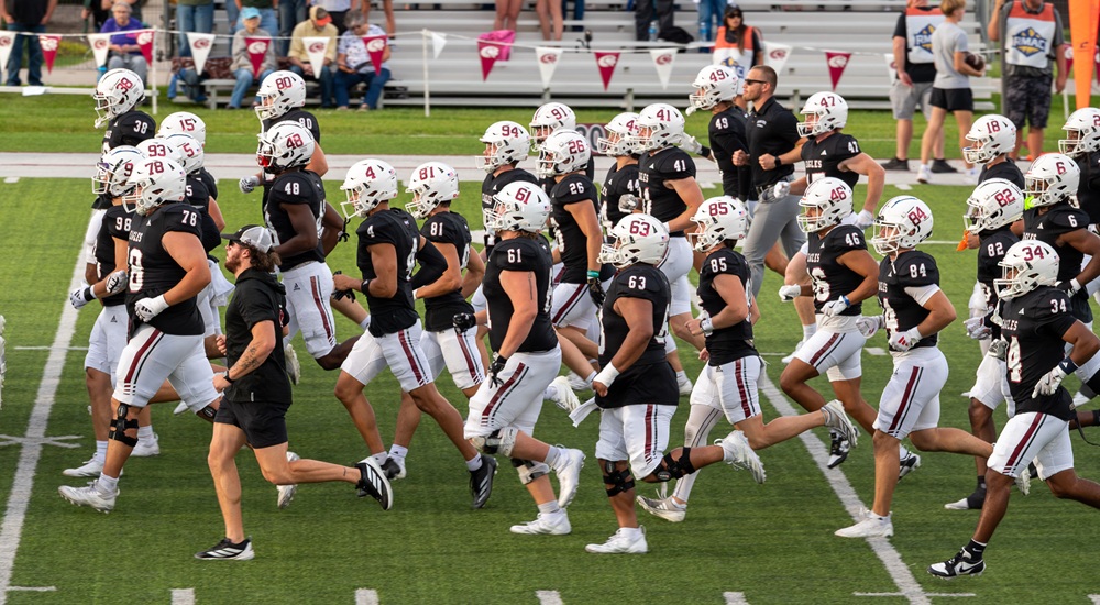 Football players taking the field with coaches