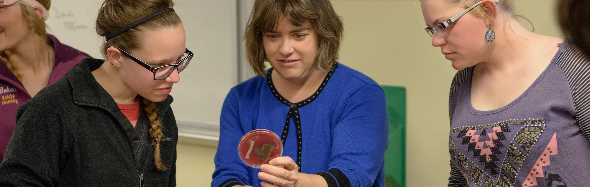 Students and a Biology professor examine a lab sample