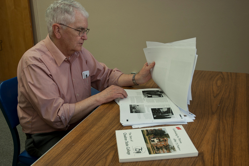 Con Marshall peruses a proof copy of the centennial history book as a copy of the 75th anniversary book is shown in the foreground.