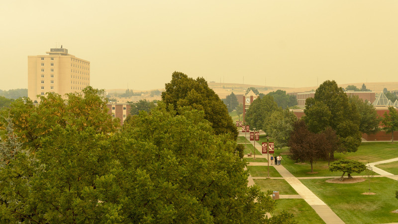 A group of students walk east across the Chadron State College campus as haze and ash from wildfires in the region move over Chadron on Thursday. (Photo by Daniel Binkard)