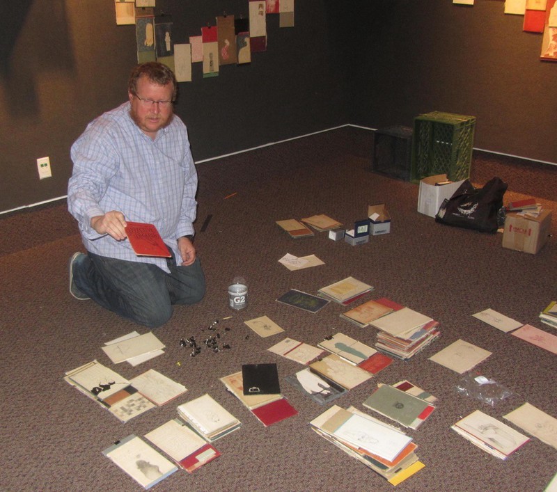 Artist Todd Christensen holds one of the book covers that will be mounted on the wall.