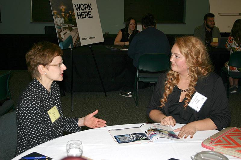 Chadron State College graphic design student Serena Brooks of Glenrock, Wyo., right, discusses her portfolio with an advertising professional