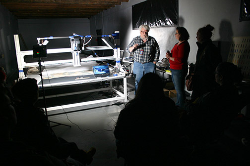 Mark Mackenzie, center, explains a high tech camera and lighting system that uses multiple spectra of light to uncover layers of paint, minerals or cotton fibers on an animal hide in the New Mexico History Museum.