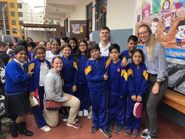 Army ROTC cadets, from left, Kaelyn Kaul of South Dakota School of Mines, and Chadron State College students Greg McCallum of Chadron, and Kalli Talbot of Rapid City, S.D., pose with Venezuelan refugees at a school in Lima, Peru, during a summer 2019 Cadet Coalition Warfighter Program exchange.