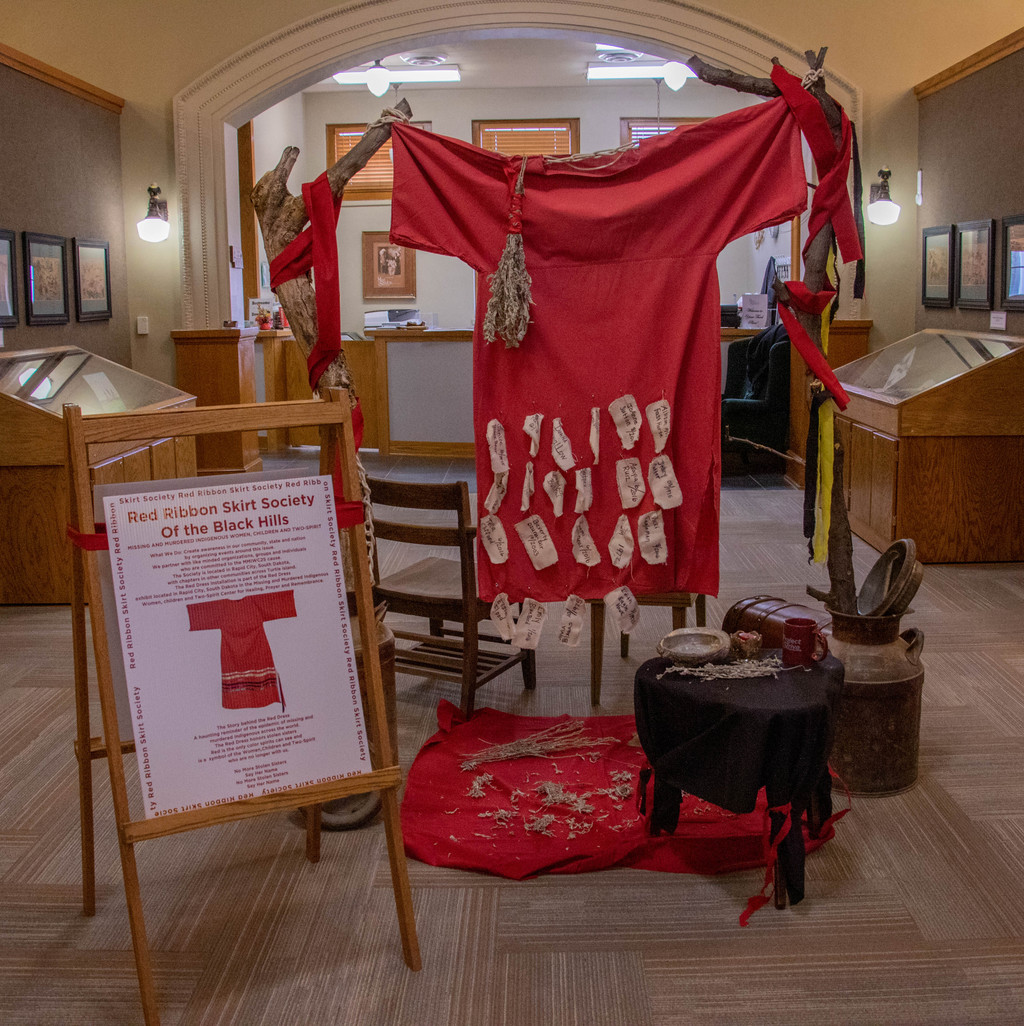 A display coordinated by Chadron State College intern Celeste Lee in the Mari Sandoz High Plains Heritage Center in honor of missing and murdered Indigenous women created by the Red Ribbon Skirt Society of the Black Hills.