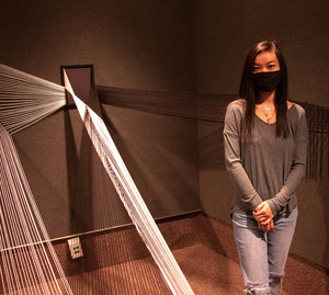 Chadron State College graphic design major Mia poses with her honorable mention string art installation Collide