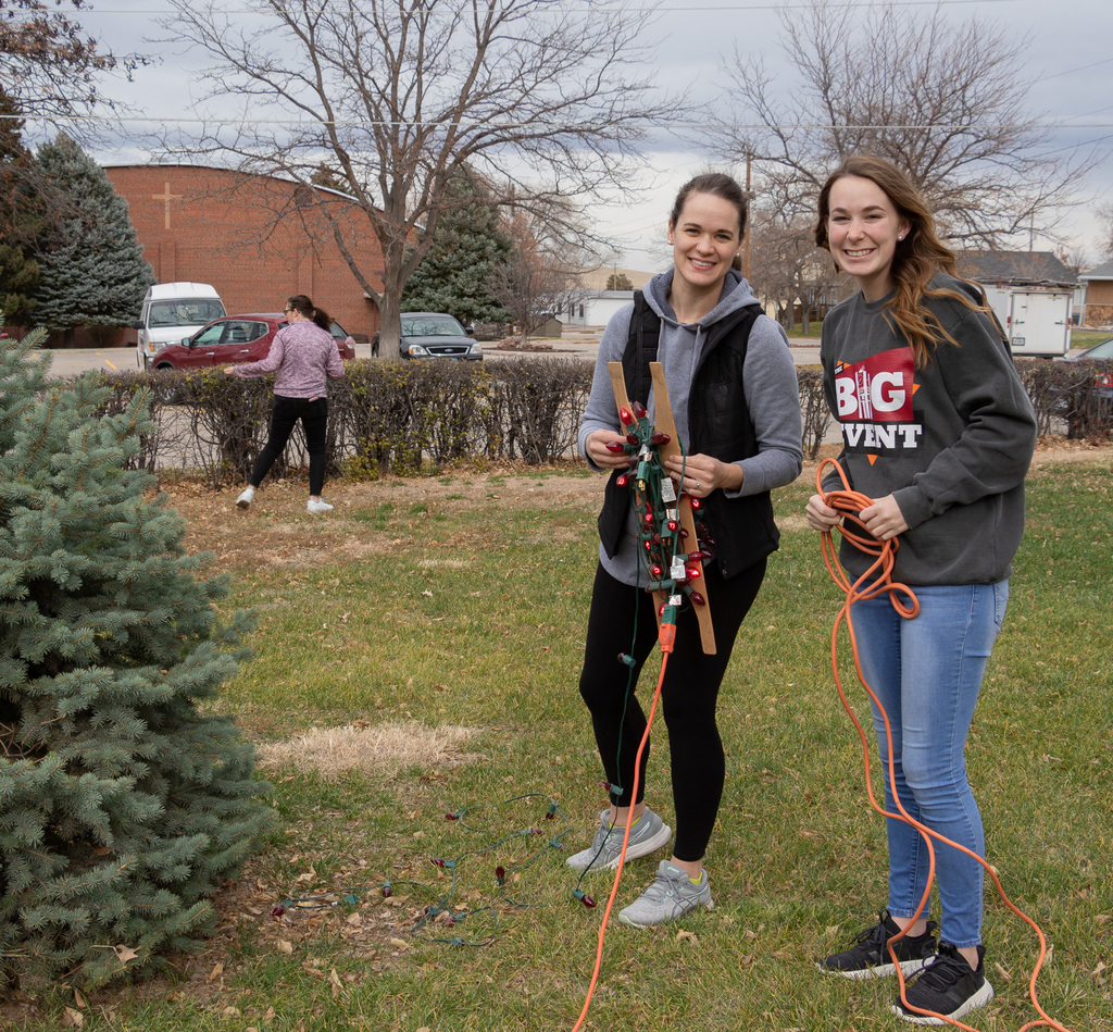 Two CSC students string up Christmas lights on a tree outside of Chadron Primary School.