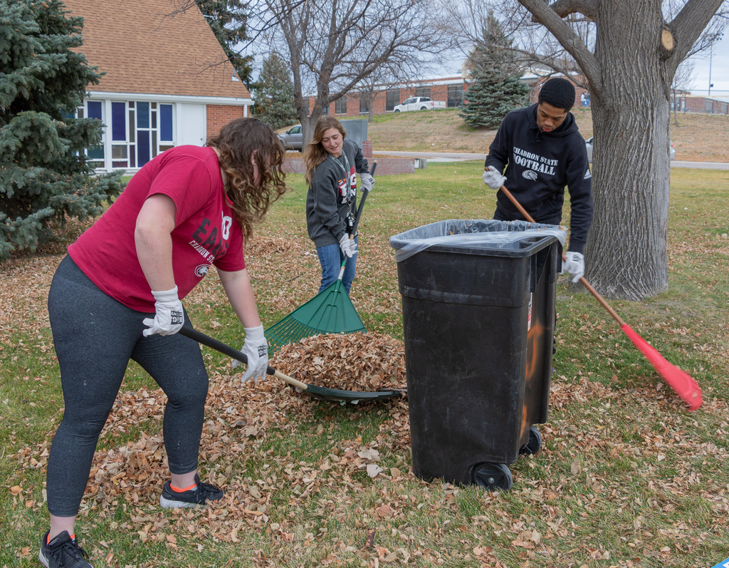 Three CSC students rake leaves outside of the Chadron Primary School.