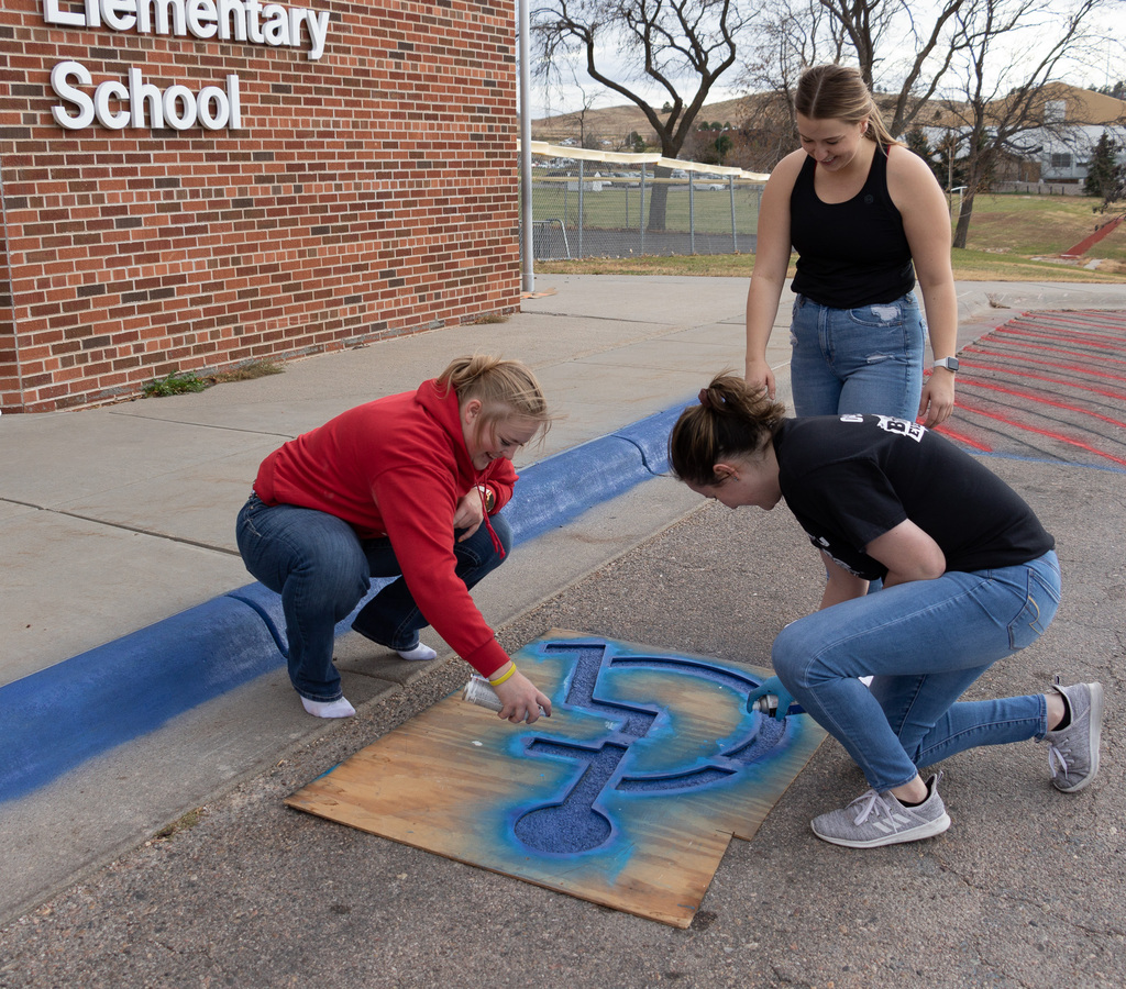 Three CSC students spray paint a handicaps parking spot to help out with the construction of the CSC Math and Science Building.