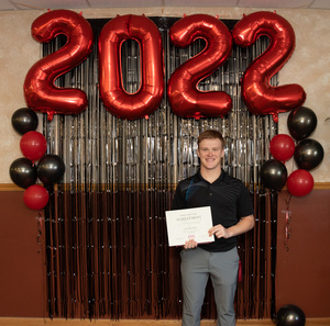 One student poses for a photo in front of a 2022 backdrop.