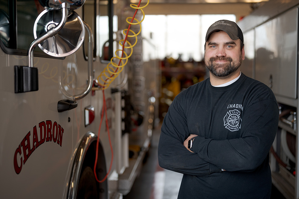 Chadron Volunteer Fire Department Chief Branden Martens stands next to the vehicles at the fire department in April 2022.