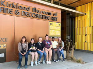 Five students and one staff member pose outside of Denver Art Museum.