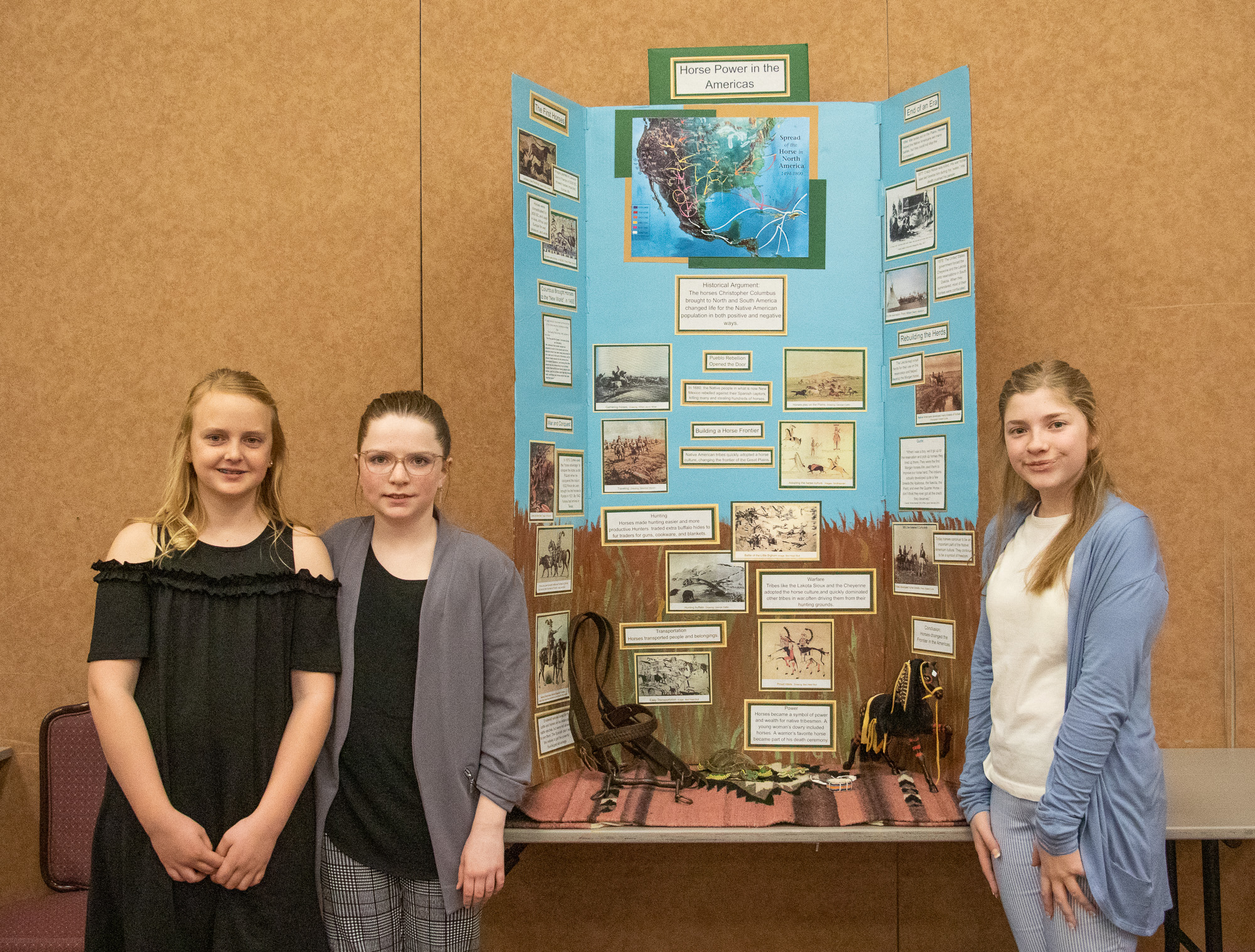 Three girls standing by a poster display