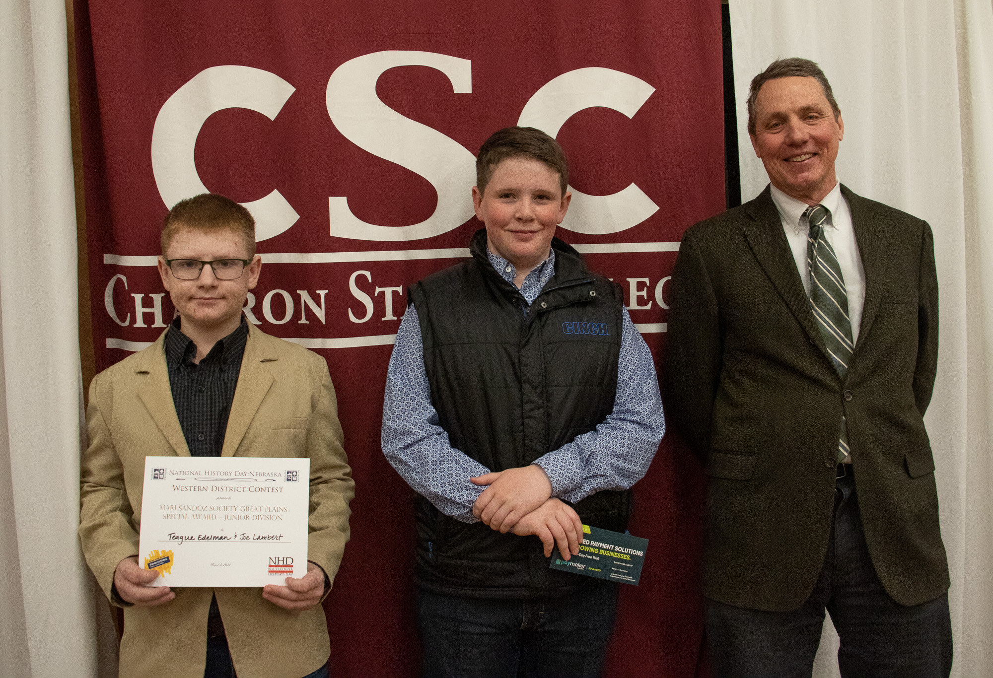 Two students and a professor pose with an award
