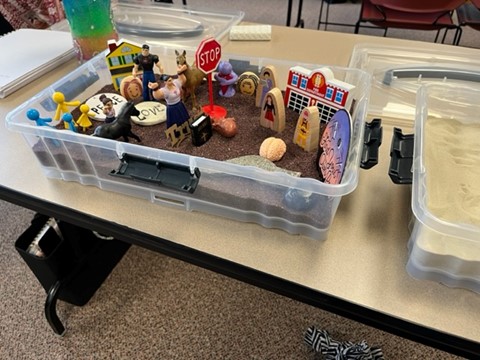 Plastic tote with sand and miniature figurines