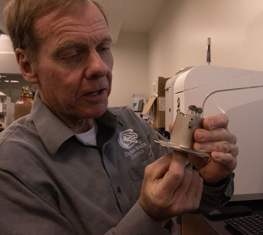 Close-up of professor holding small piece of equipment