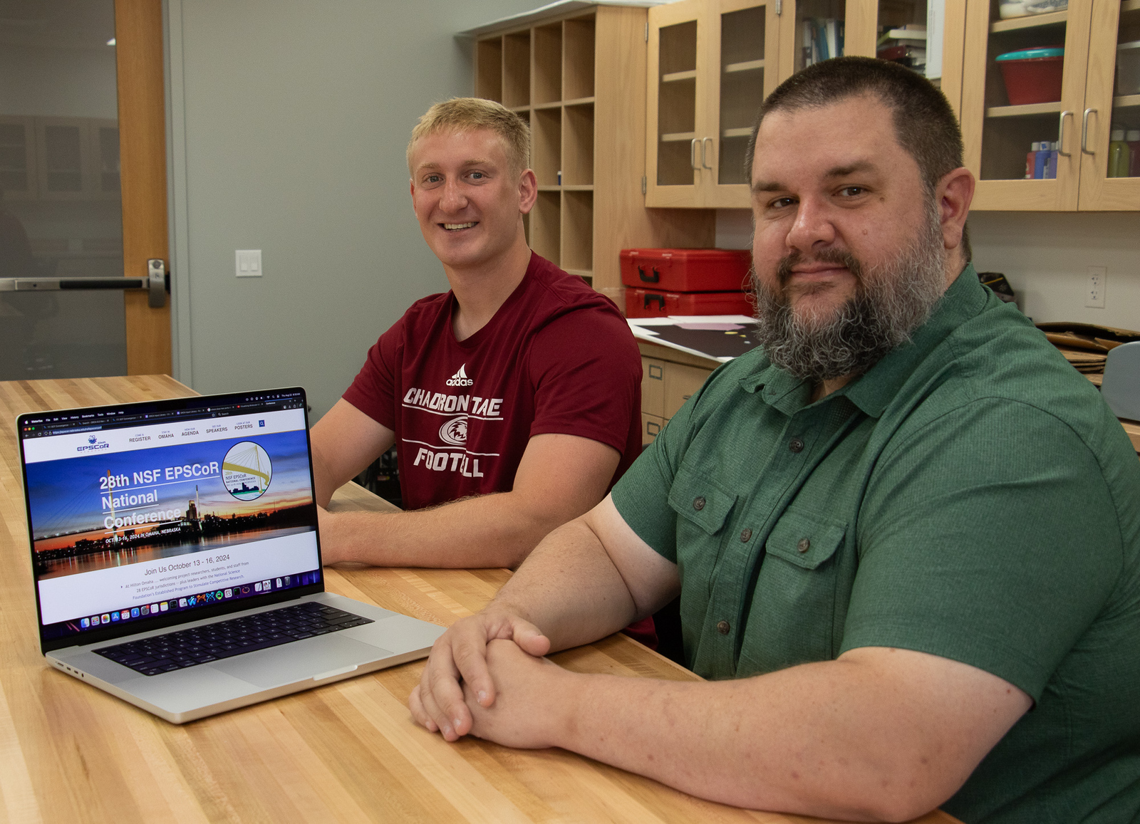 Two men sitting in a lab by a laptop