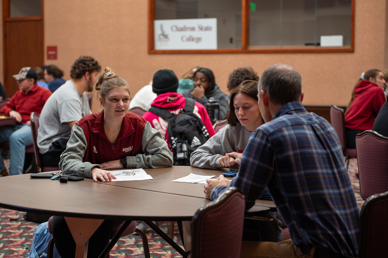 Students and faculty talking around a table