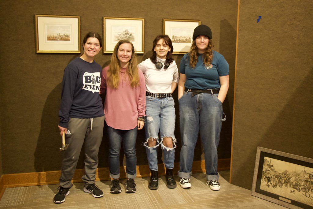 Four students standing with art exhibit