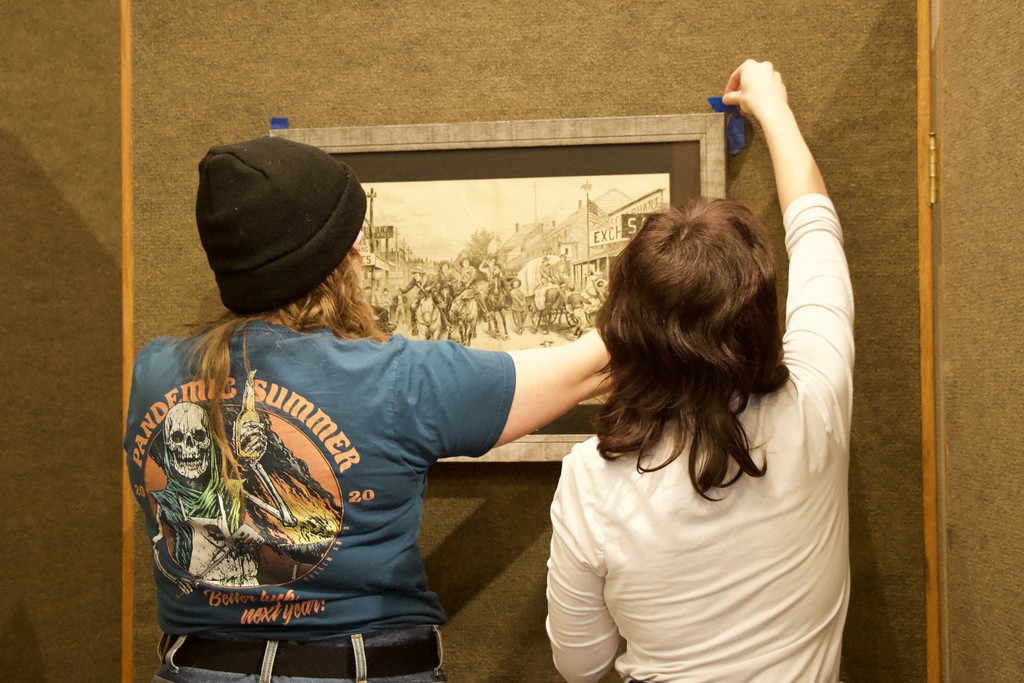 Two students hanging a piece of art