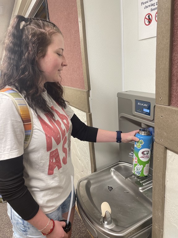 Woman at a water fountain filling a water bottle