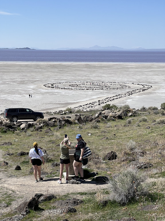 Adult on the shore of the Great Salt Lake by a manmade rock formation