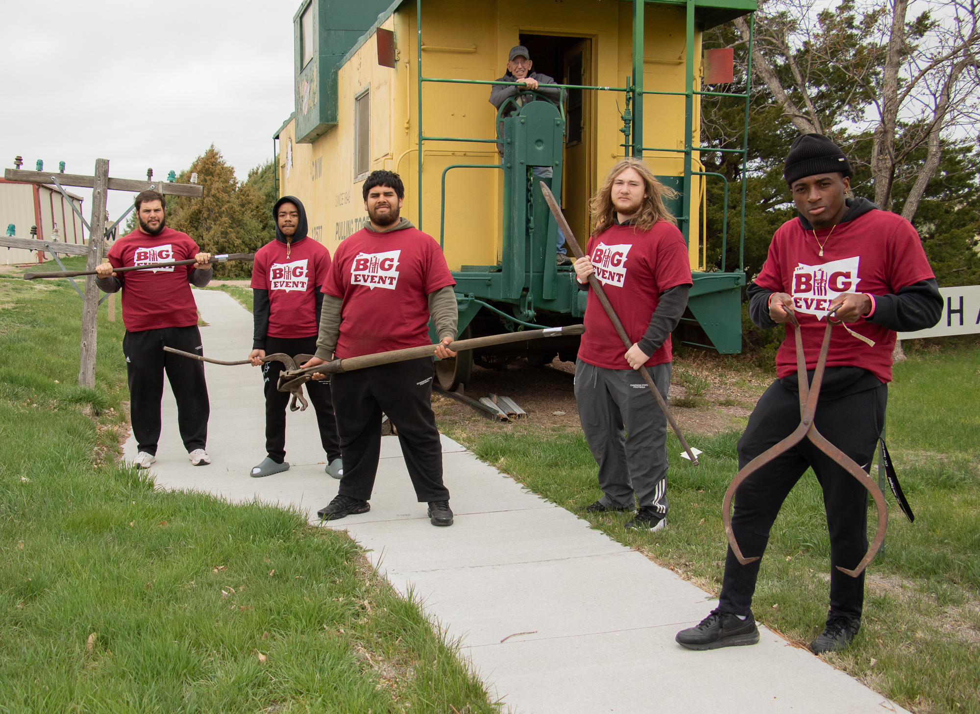 Students posing by a train car with historical farm implements