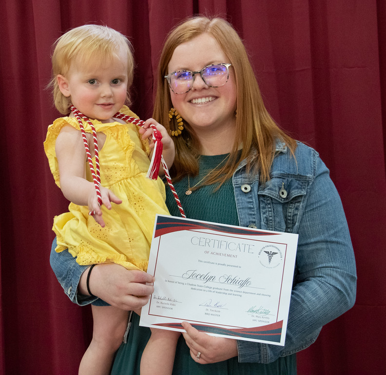 Student posing with award and infant daughter
