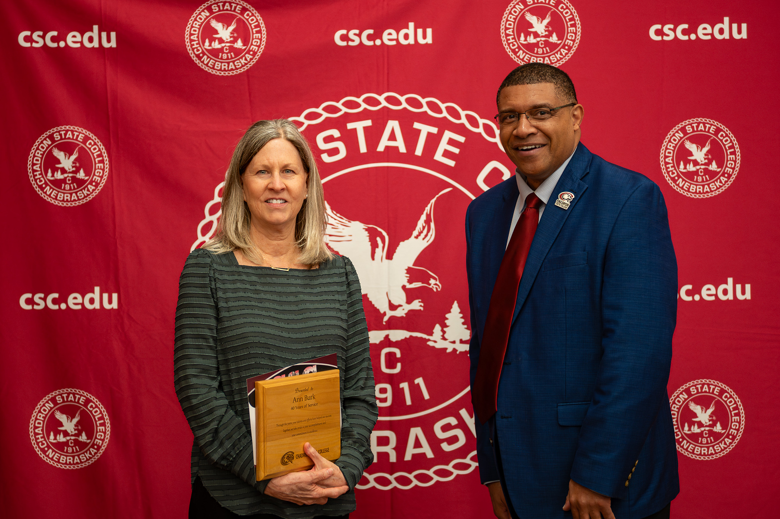 Two adults posing with an award