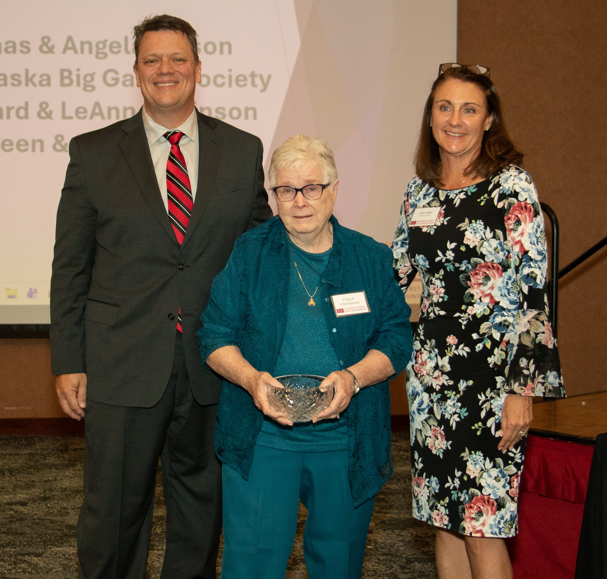 Three people posing with an award