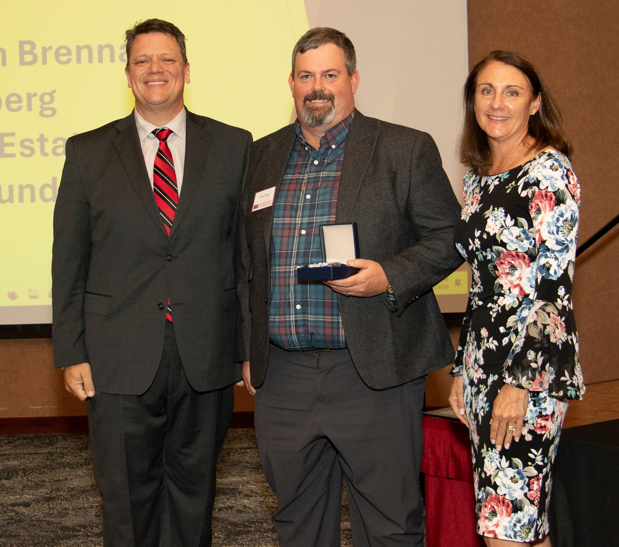 Three people posing with an award