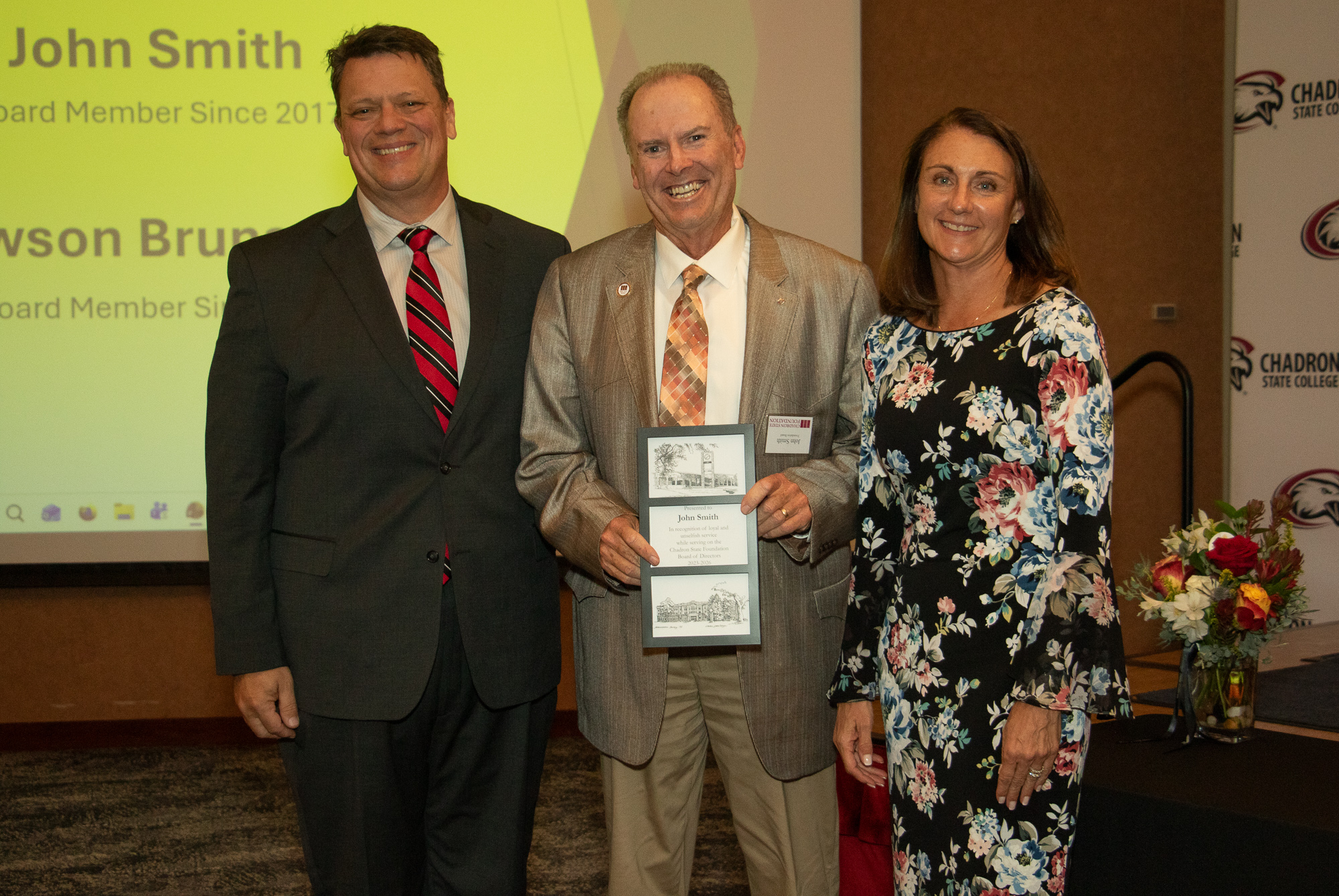 Three people posing with an award