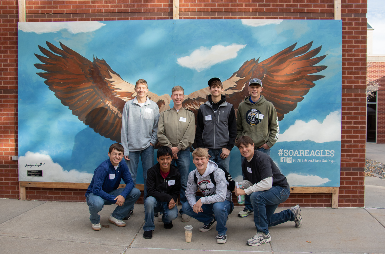 Group of high school students posing at eagle mural