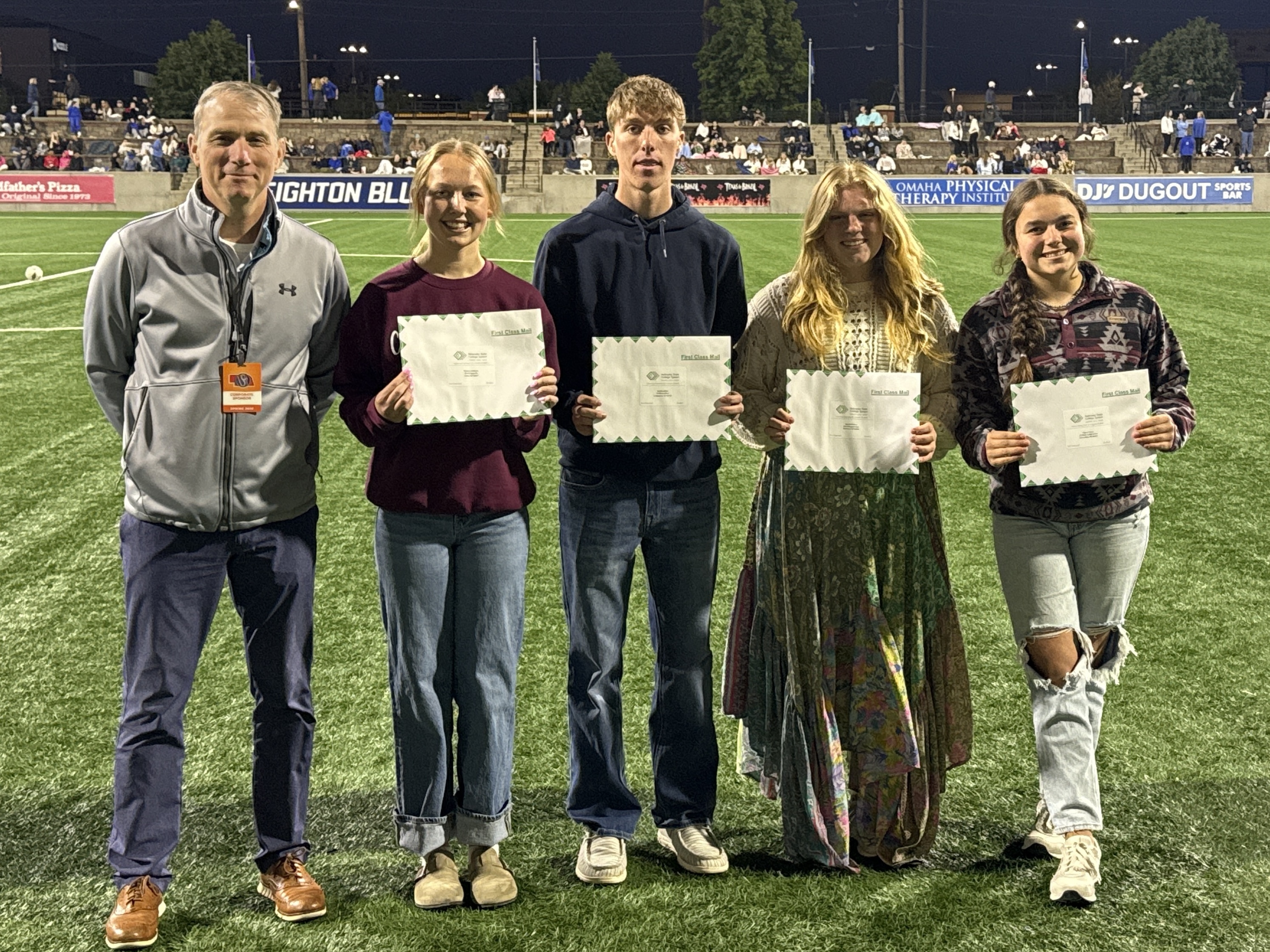Group posing with certificates on a field