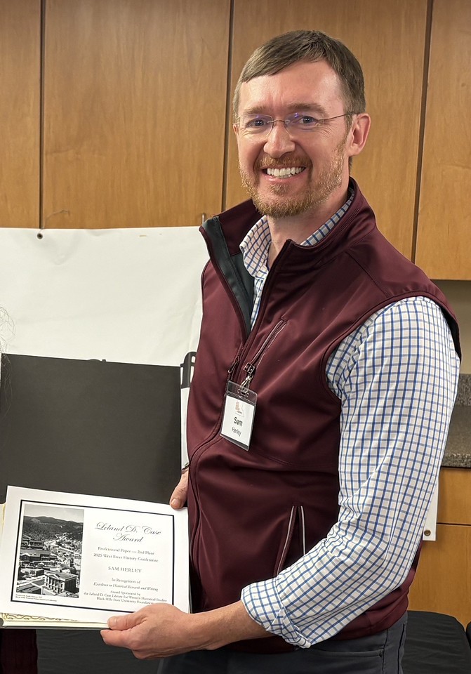 Professor poses with award