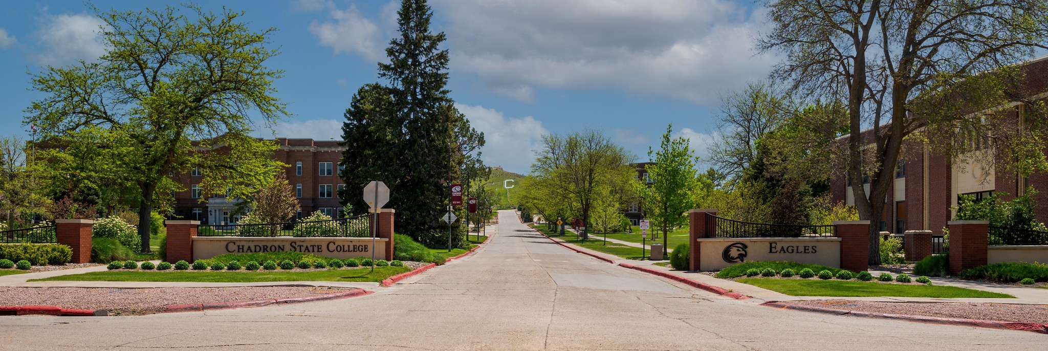 Blue and cloudy sky with the entrance of Chadron State College presented in brick.