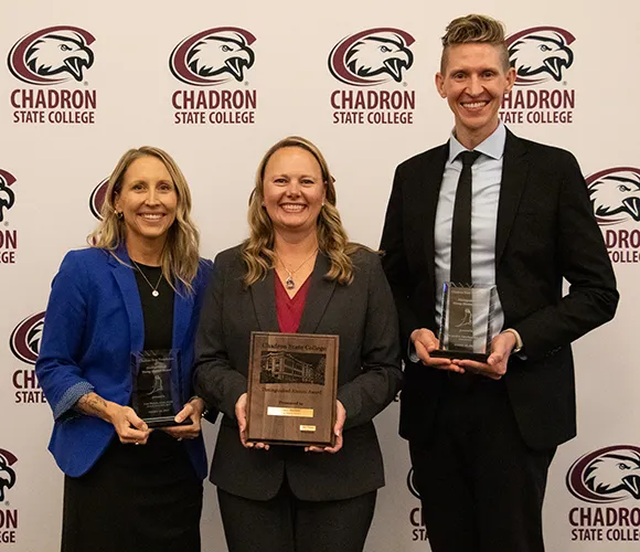 Three people posing with awards