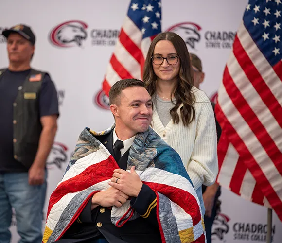 Armed forces member and spouse being honored with a ceremonial flag