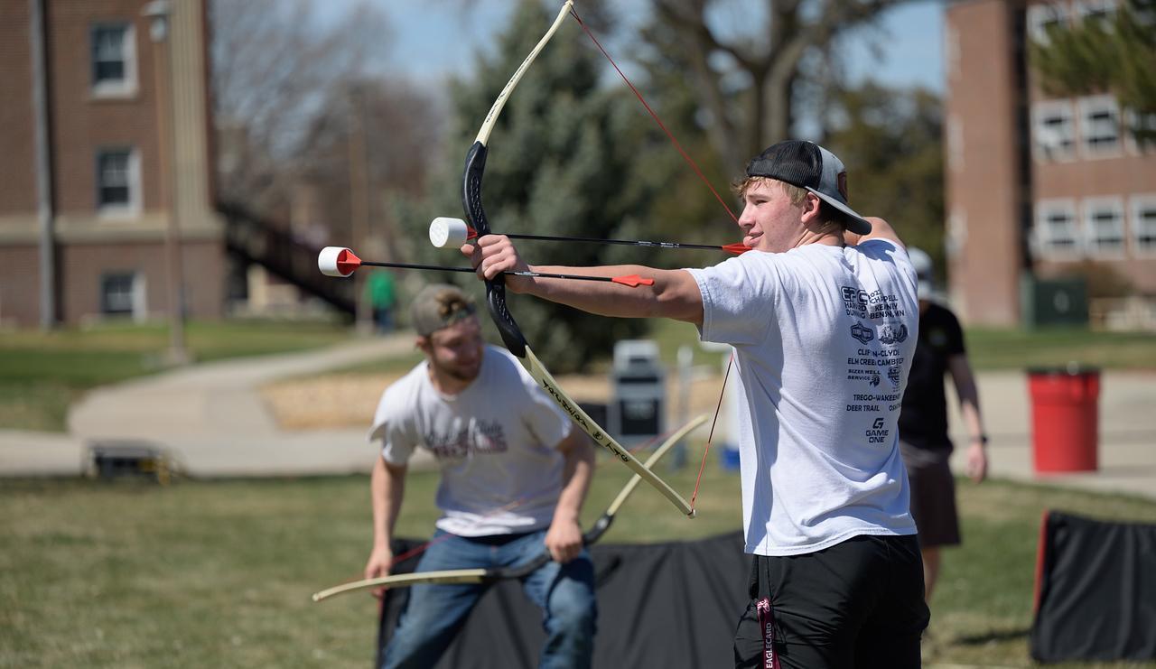 Student shooting a bow and foam arrows at the Inauguration block party